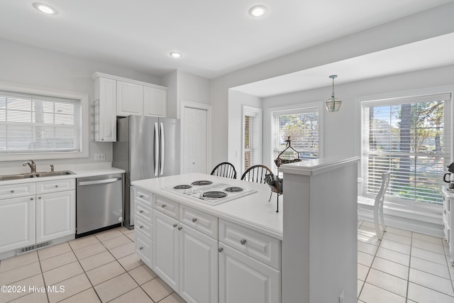 kitchen featuring sink, hanging light fixtures, light tile patterned floors, white cabinets, and appliances with stainless steel finishes