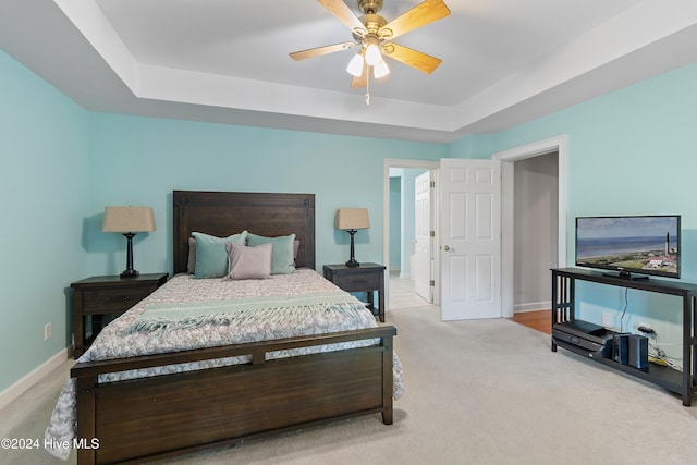 carpeted bedroom featuring a raised ceiling and ceiling fan