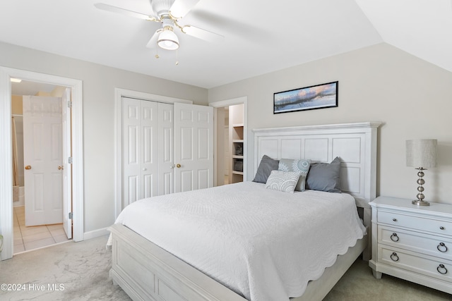 bedroom with ceiling fan, a closet, light carpet, and vaulted ceiling