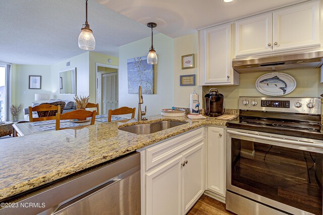 2000 New River Inlet Rd Unit 1203, North Topsail Beach, NC 28460 - kitchen featuring stainless steel appliances, under cabinet range hood, a sink, white cabinets, and hanging light fixtures