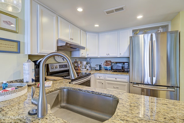 2000 New River Inlet Rd Unit 1203, North Topsail Beach, NC 28460 - kitchen with appliances with stainless steel finishes, under cabinet range hood, white cabinets, recessed lighting, and light stone countertops