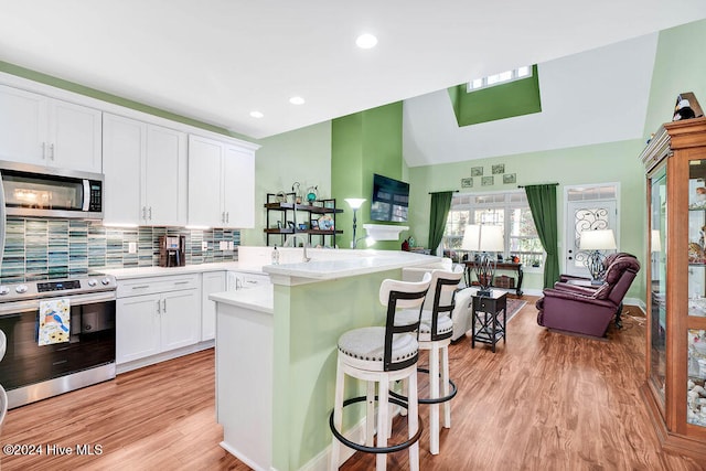 kitchen featuring a breakfast bar, white cabinets, light wood-type flooring, and appliances with stainless steel finishes