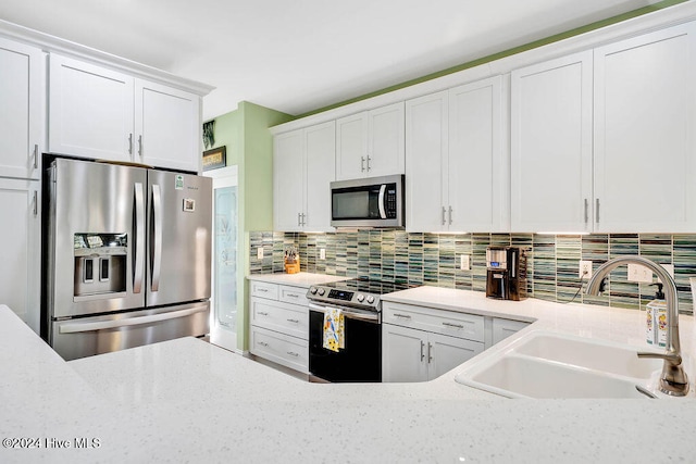 kitchen with white cabinets, sink, light stone countertops, appliances with stainless steel finishes, and tasteful backsplash