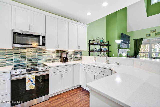 kitchen featuring decorative backsplash, stainless steel appliances, sink, white cabinets, and light hardwood / wood-style floors