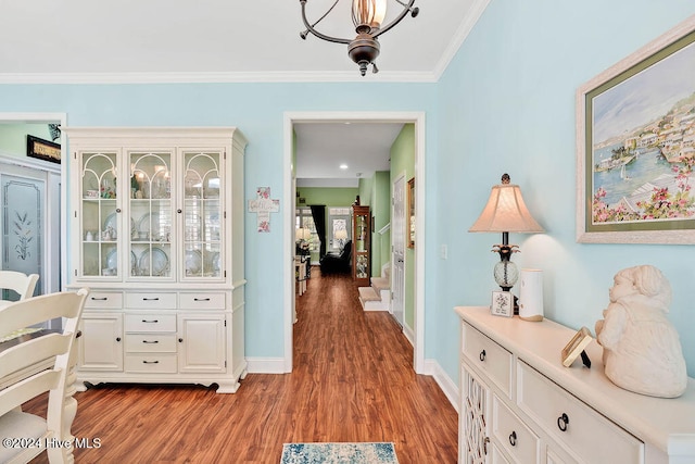 hall featuring light hardwood / wood-style floors, an inviting chandelier, and ornamental molding