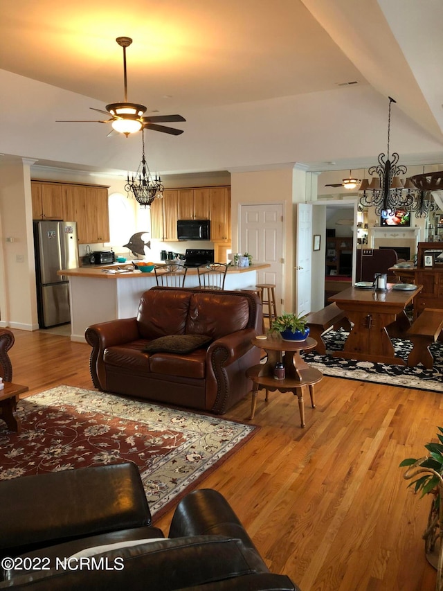 living room with light hardwood / wood-style floors and ceiling fan with notable chandelier