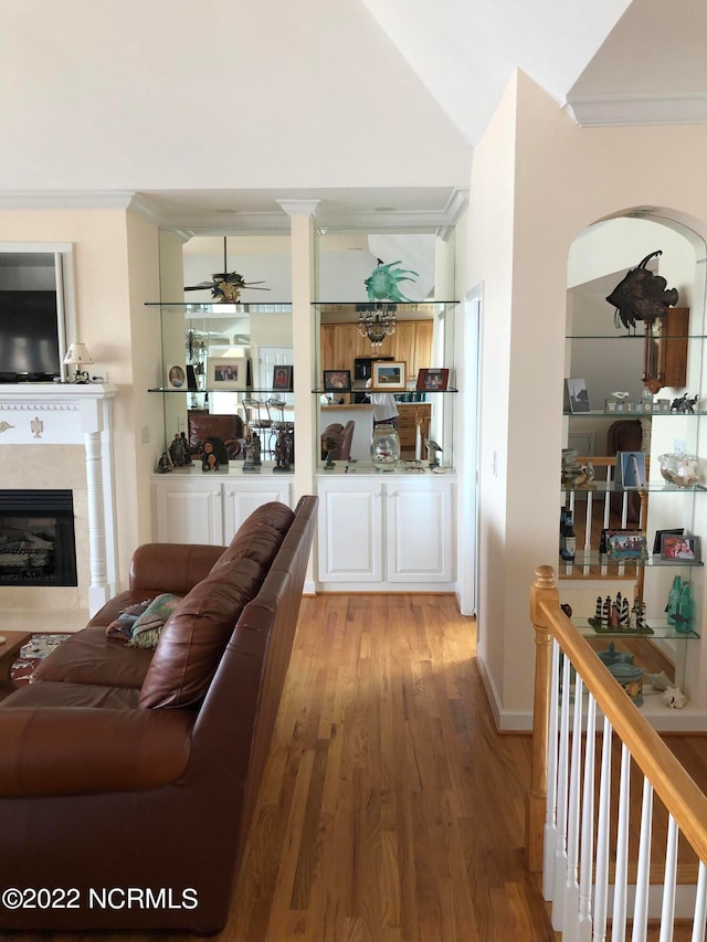 living room with ceiling fan, crown molding, lofted ceiling, and light wood-type flooring