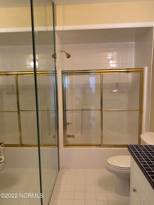 full bathroom with tile patterned flooring, toilet, combined bath / shower with glass door, and vanity