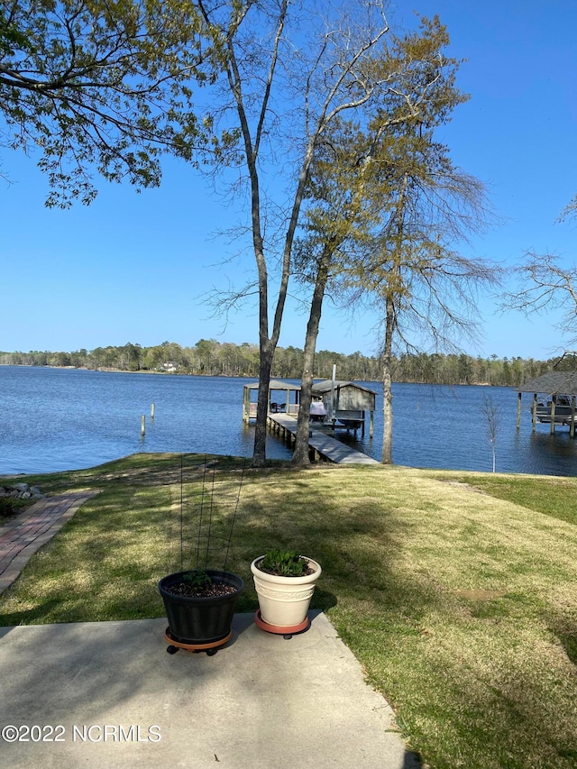 view of dock featuring a lawn and a water view