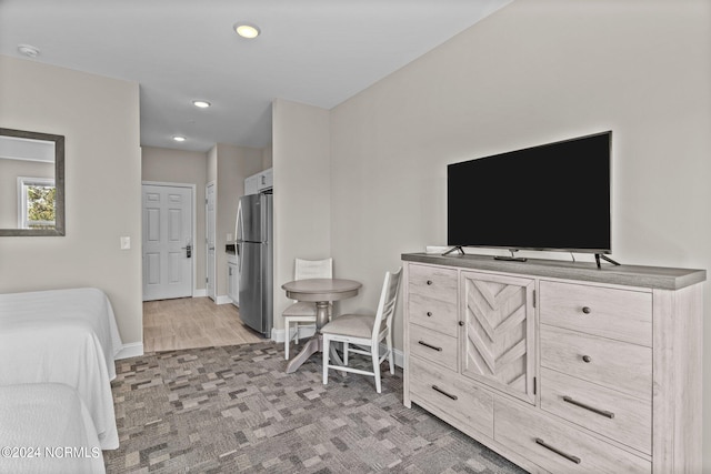 bedroom featuring stainless steel refrigerator and light hardwood / wood-style flooring