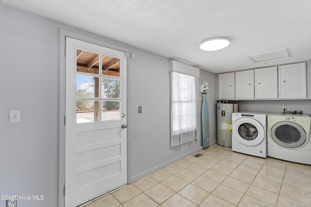 washroom with washer and dryer, water heater, cabinets, light tile patterned floors, and a textured ceiling