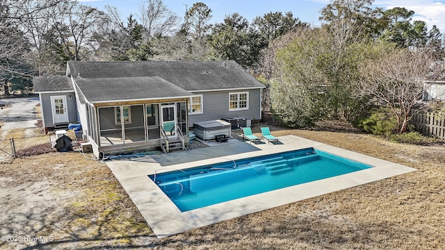 rear view of house with a swimming pool with hot tub, a sunroom, and a patio area