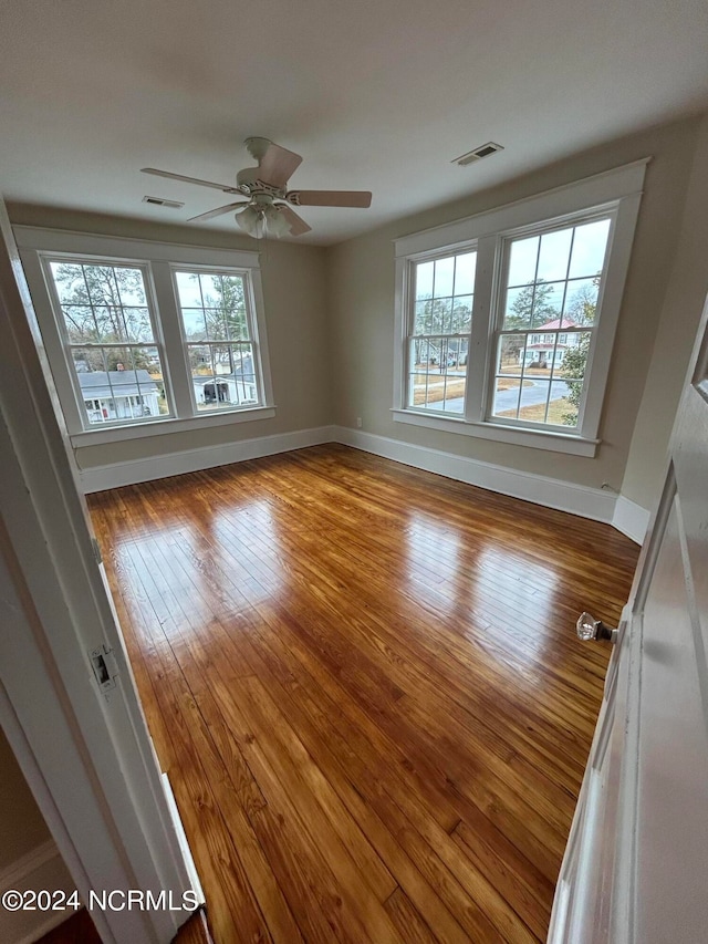 unfurnished room with wood-type flooring, a wealth of natural light, and ceiling fan