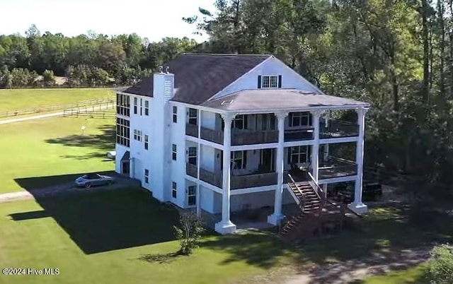 rear view of house featuring a lawn and a balcony