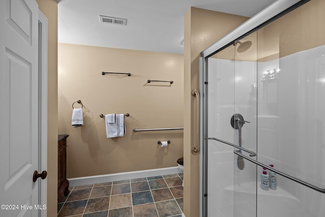 bathroom featuring a shower with door and toilet