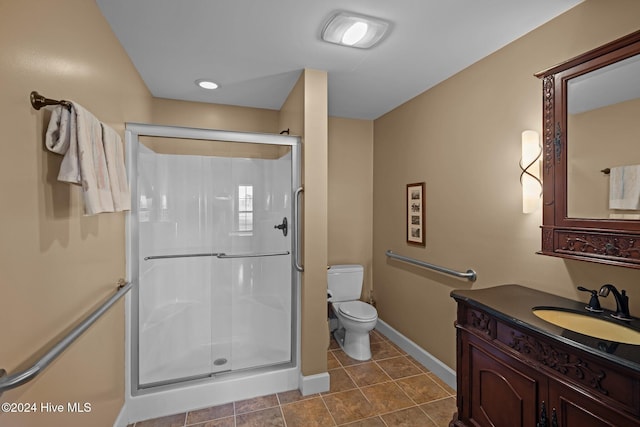 bathroom featuring tile patterned flooring, vanity, toilet, and a shower with shower door