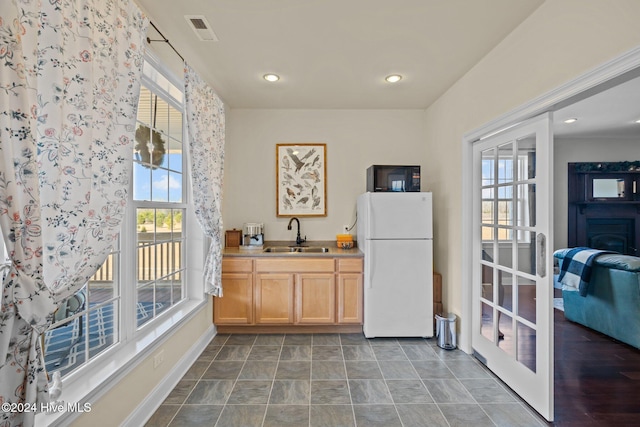 kitchen featuring light brown cabinets, white refrigerator, a healthy amount of sunlight, and sink