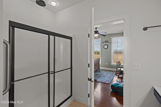 bathroom featuring ceiling fan, a shower with door, and hardwood / wood-style flooring