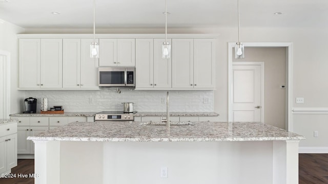 kitchen featuring pendant lighting, light stone counters, sink, and stainless steel appliances