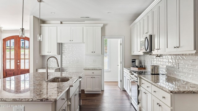 kitchen with sink, light stone counters, decorative light fixtures, white cabinets, and appliances with stainless steel finishes