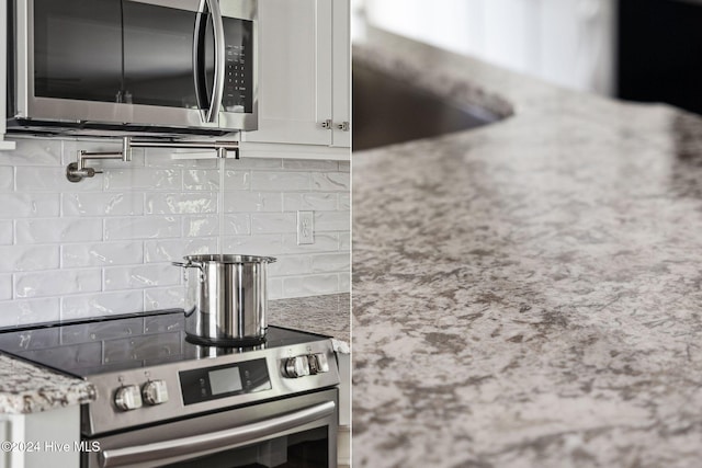 kitchen featuring light stone countertops, appliances with stainless steel finishes, backsplash, and white cabinetry