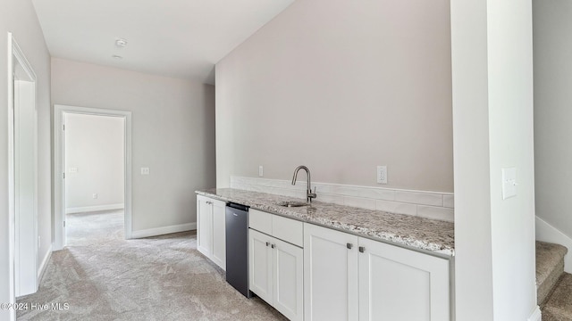 kitchen featuring white cabinets, light colored carpet, sink, stainless steel dishwasher, and light stone counters