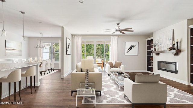 living room featuring ceiling fan with notable chandelier, dark hardwood / wood-style floors, and built in features