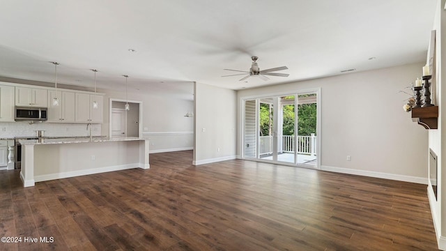 unfurnished living room with dark hardwood / wood-style floors, ceiling fan, and sink