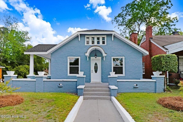 bungalow-style home with fence, a chimney, and a front lawn
