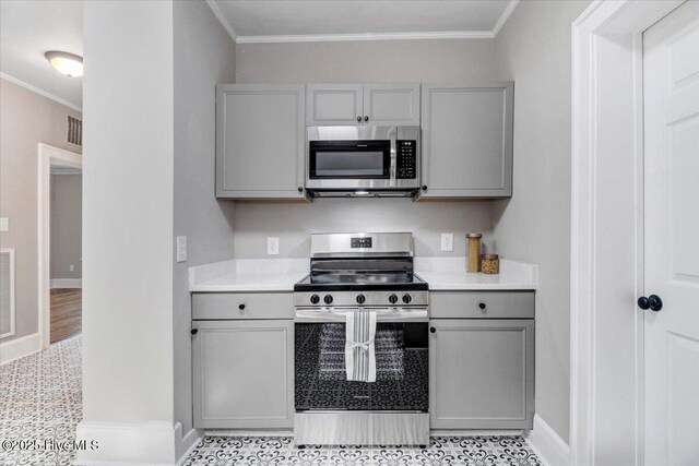 kitchen featuring crown molding, baseboards, light countertops, gray cabinets, and stainless steel appliances