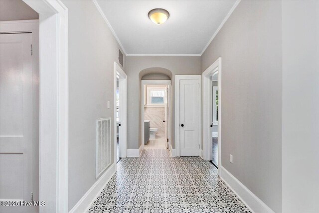 corridor with crown molding, tile patterned floors, baseboards, and visible vents