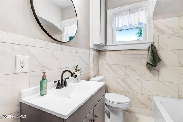 bathroom with toilet, tile walls, a bathtub, and vanity