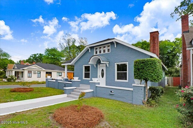 bungalow featuring a chimney and a front yard