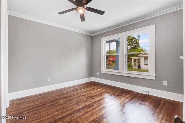 unfurnished room with ceiling fan, visible vents, baseboards, dark wood-style floors, and ornamental molding