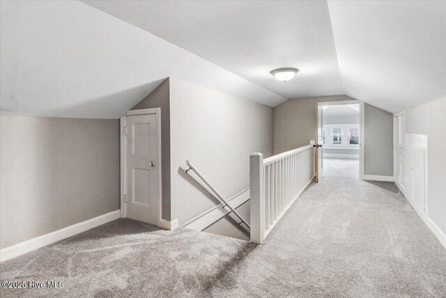 additional living space with carpet flooring, baseboards, and vaulted ceiling