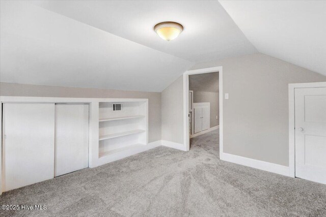 additional living space with visible vents, carpet flooring, built in features, and vaulted ceiling