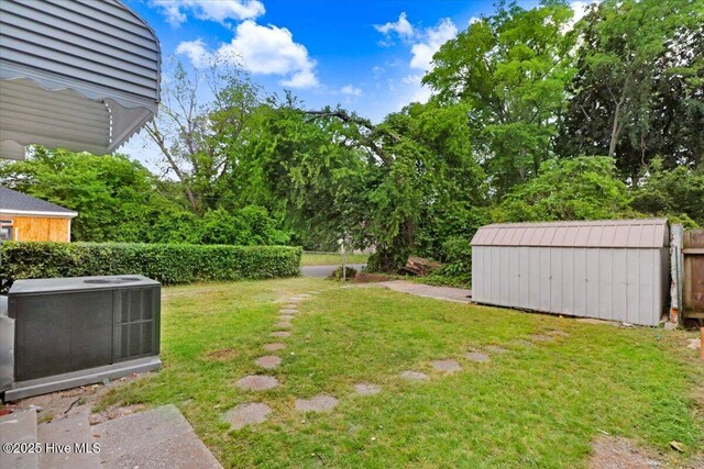 view of yard featuring a storage shed, an outdoor structure, and cooling unit