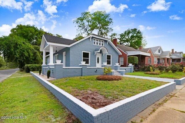 bungalow-style house featuring brick siding, a front lawn, and a chimney