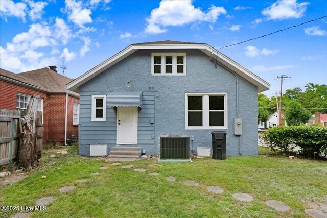 back of property featuring a lawn, fence, cooling unit, and stucco siding