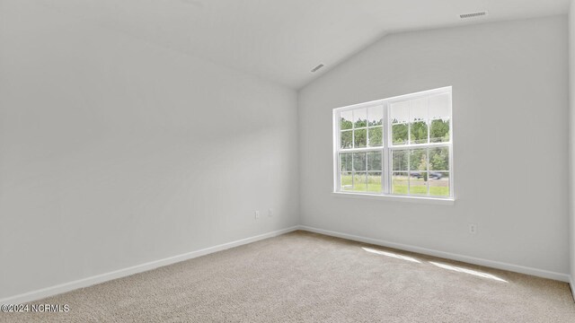 carpeted empty room with lofted ceiling