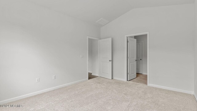 unfurnished bedroom featuring lofted ceiling and light carpet