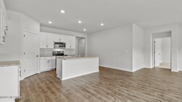 kitchen featuring white cabinetry, light hardwood / wood-style flooring, electric range, and an island with sink