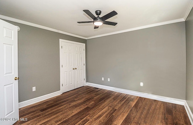 unfurnished bedroom with ceiling fan, ornamental molding, dark wood-type flooring, and a closet