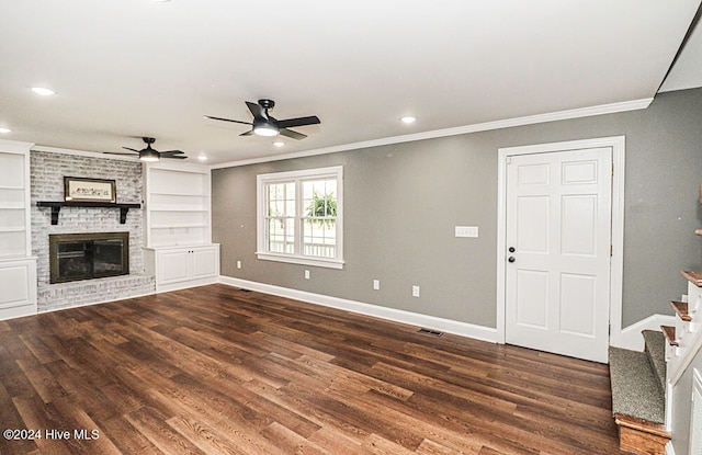 unfurnished living room with dark wood-type flooring, a brick fireplace, ceiling fan, built in features, and ornamental molding