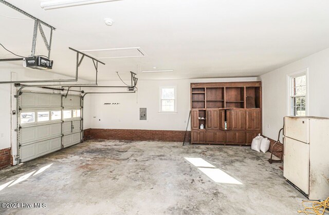 garage featuring electric panel, white fridge, and a garage door opener