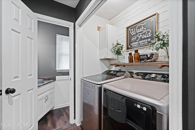 clothes washing area featuring washing machine and dryer, cabinets, dark wood-type flooring, and a textured ceiling