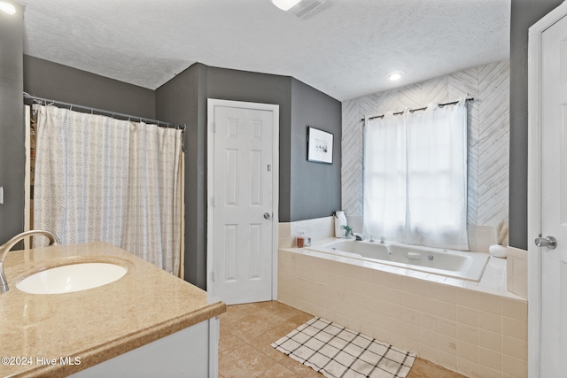 bathroom with tiled bath, tile patterned flooring, vanity, and a textured ceiling