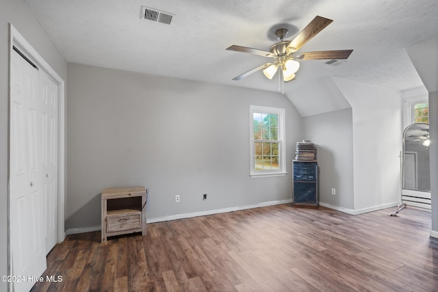 interior space with a textured ceiling, ceiling fan, dark wood-type flooring, and lofted ceiling