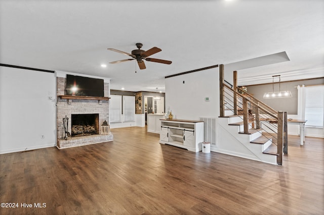 unfurnished living room featuring ceiling fan, wood-type flooring, and a brick fireplace