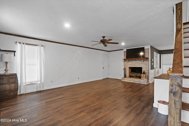 unfurnished living room featuring dark hardwood / wood-style floors, ceiling fan, crown molding, and a fireplace